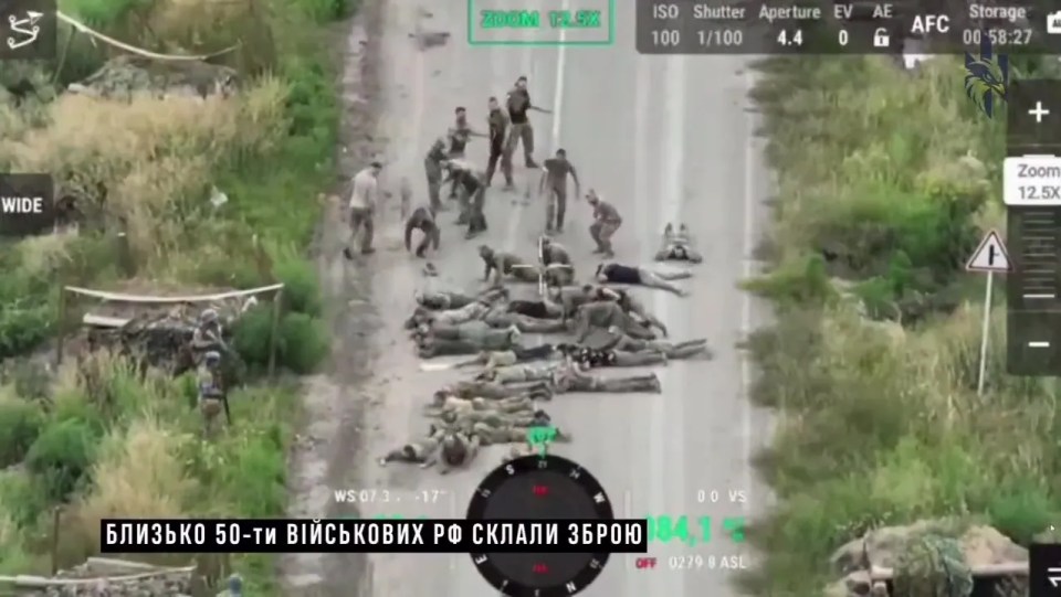 Russian soldiers lie on a road after surrendering in their own country