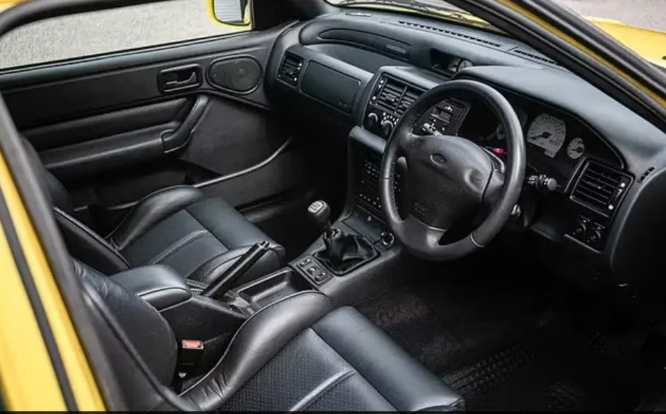 the interior of a yellow ford car with black leather seats