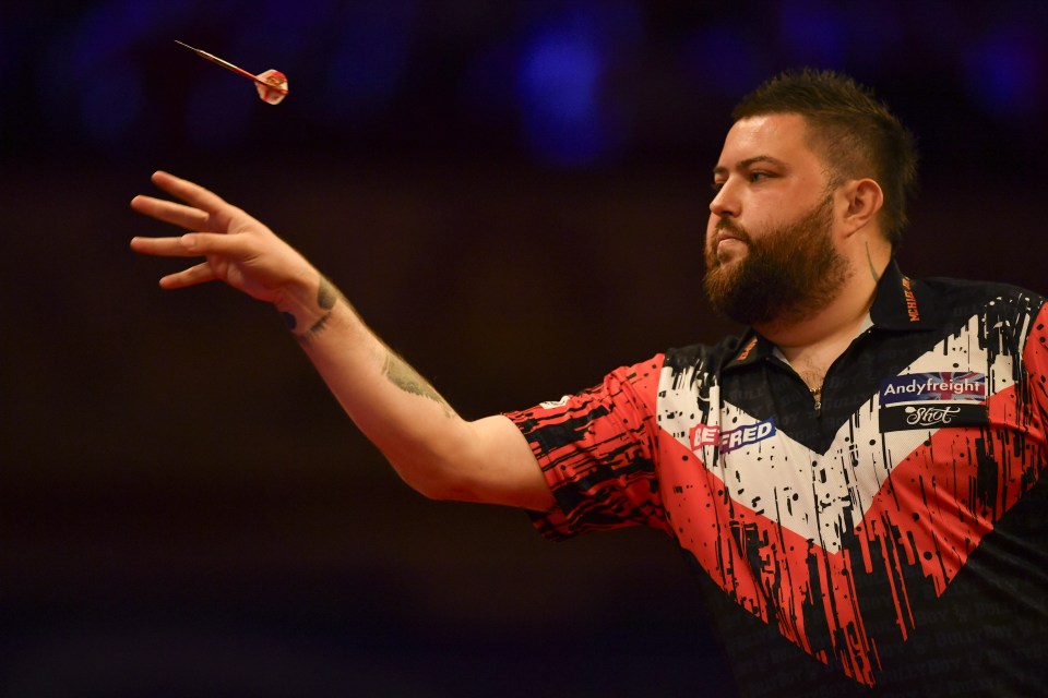 a man wearing a shirt that says andy freight throws a dart