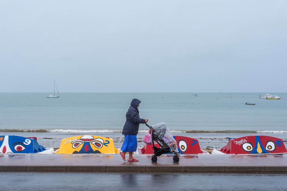 a woman pushes a stroller in front of a row of umbrellas that say douglas