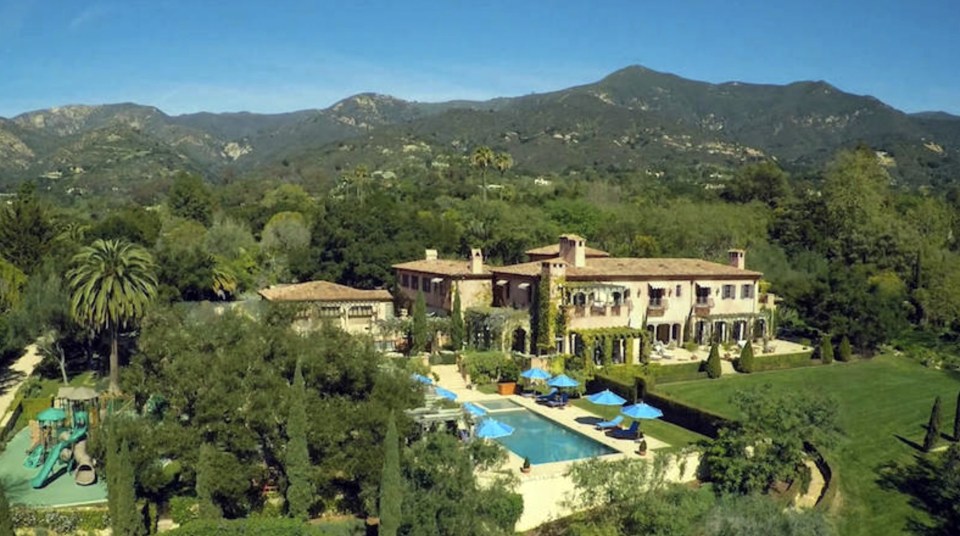 an aerial view of a large house with mountains in the background