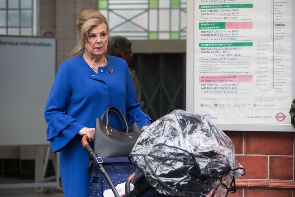 a woman pushing a stroller in front of a sign that says service information