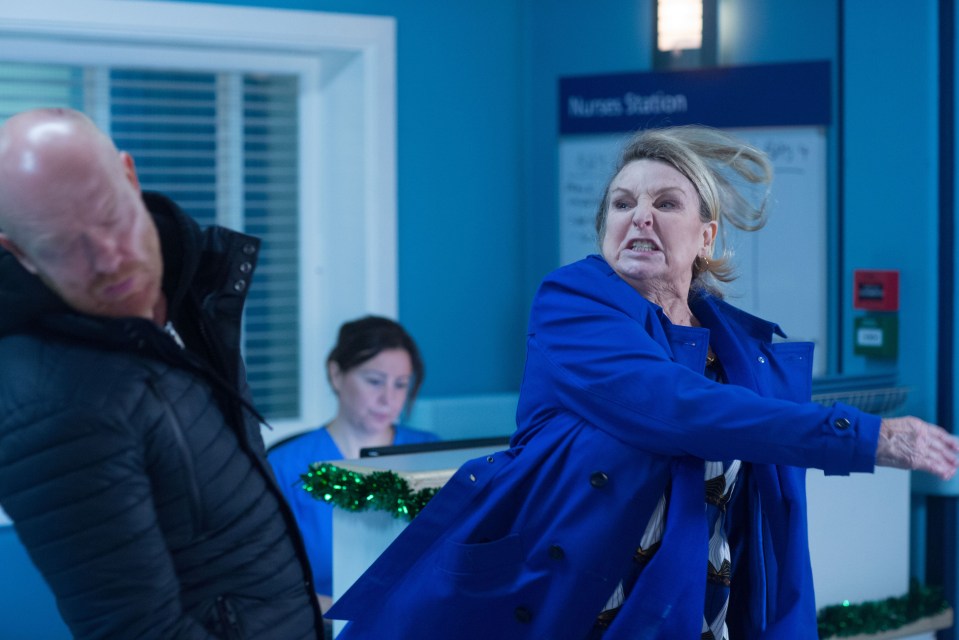 a woman in a blue coat is standing in front of a sign that says nurse station