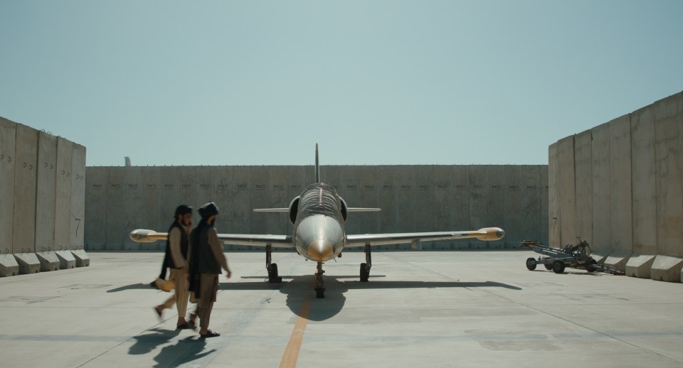 two men walking in front of a plane that has the letters a and b on it