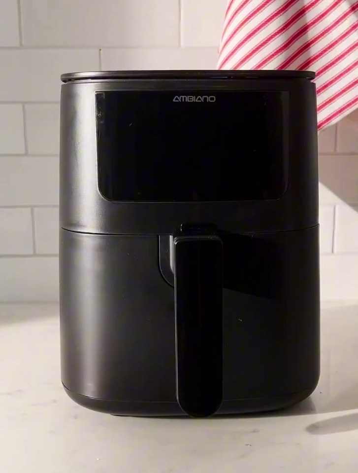 a black air fryer is sitting on a counter next to a towel