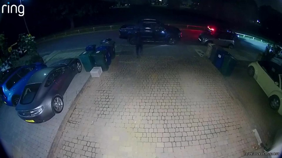 a ring camera shows cars parked in a driveway at night