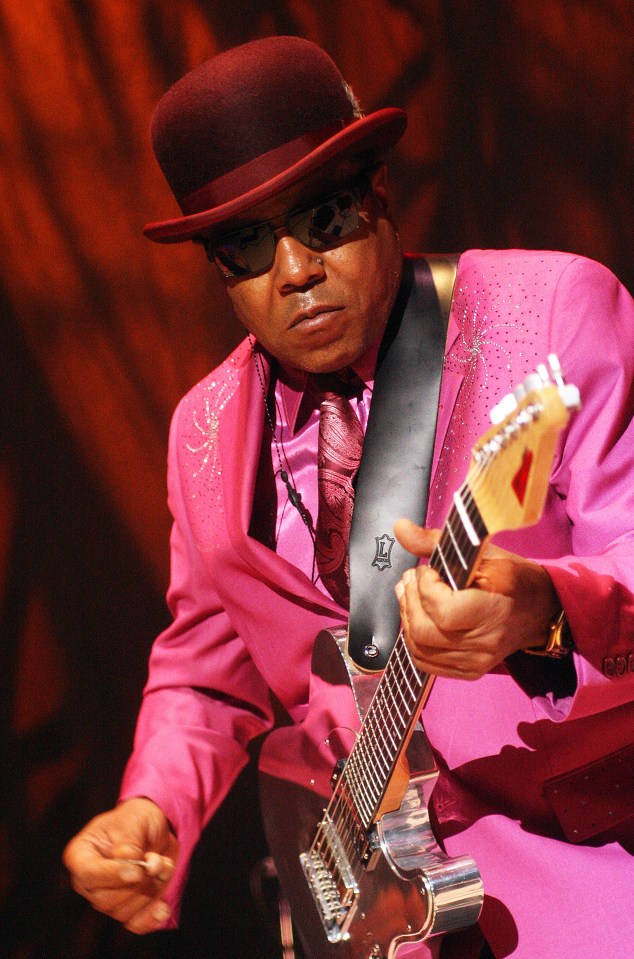 a man in a pink suit is playing a guitar