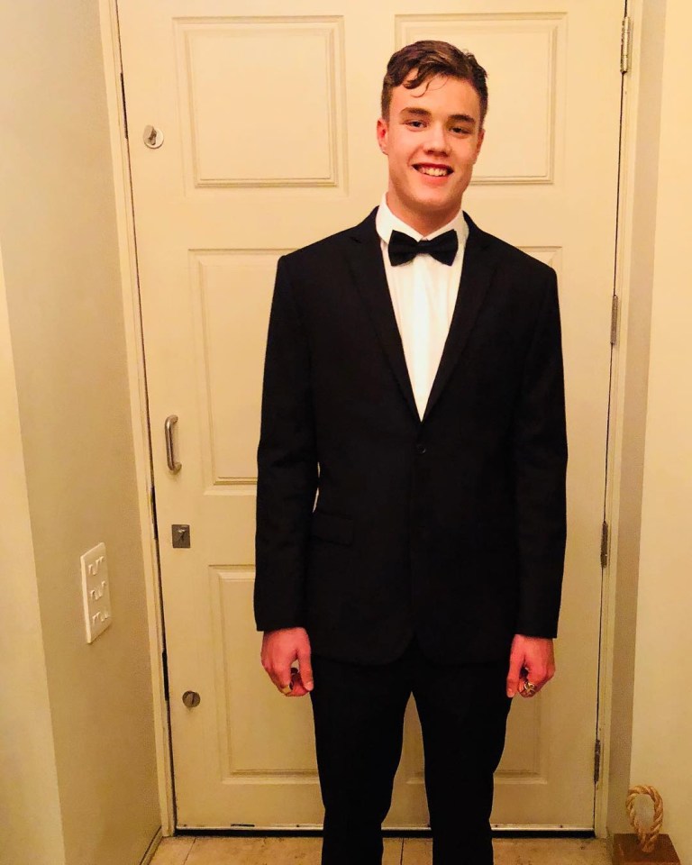 a young man in a tuxedo and bow tie stands in front of a door