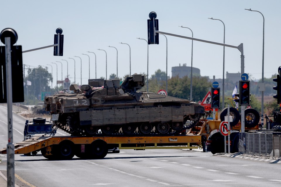 A truck carrying a tank drives toward Israel’s northern border with Lebanon on Saturday