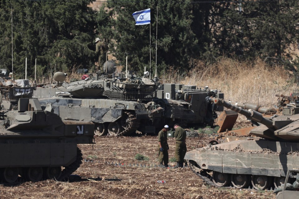 two soldiers stand in front of a tank with the number 21 on the side