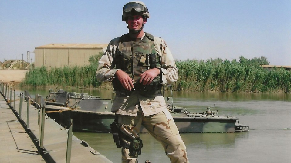 a man in a military uniform stands in front of a body of water