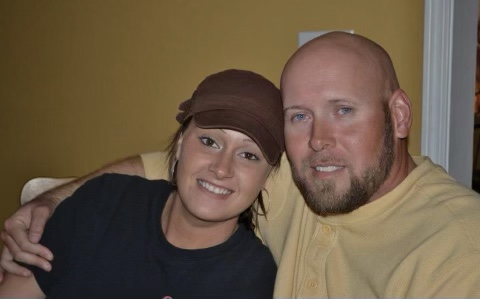 a man and a woman are posing for a picture and the woman is wearing a hat