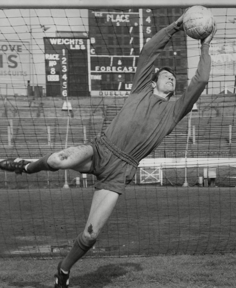 a black and white photo of a man catching a soccer ball