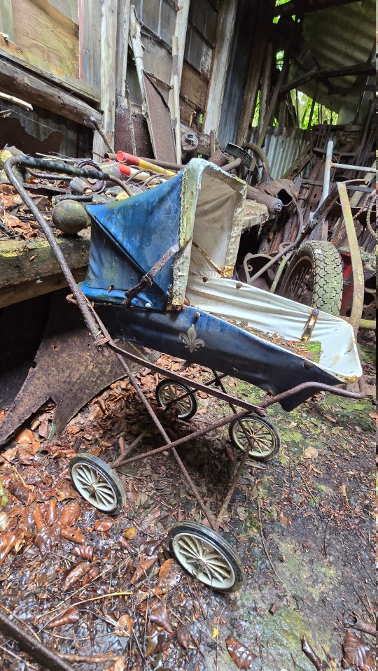 an old rusty stroller sits in a pile of junk