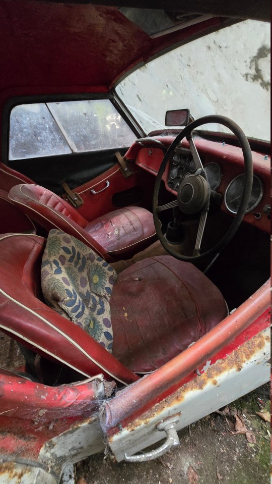 the inside of an old red car with a steering wheel