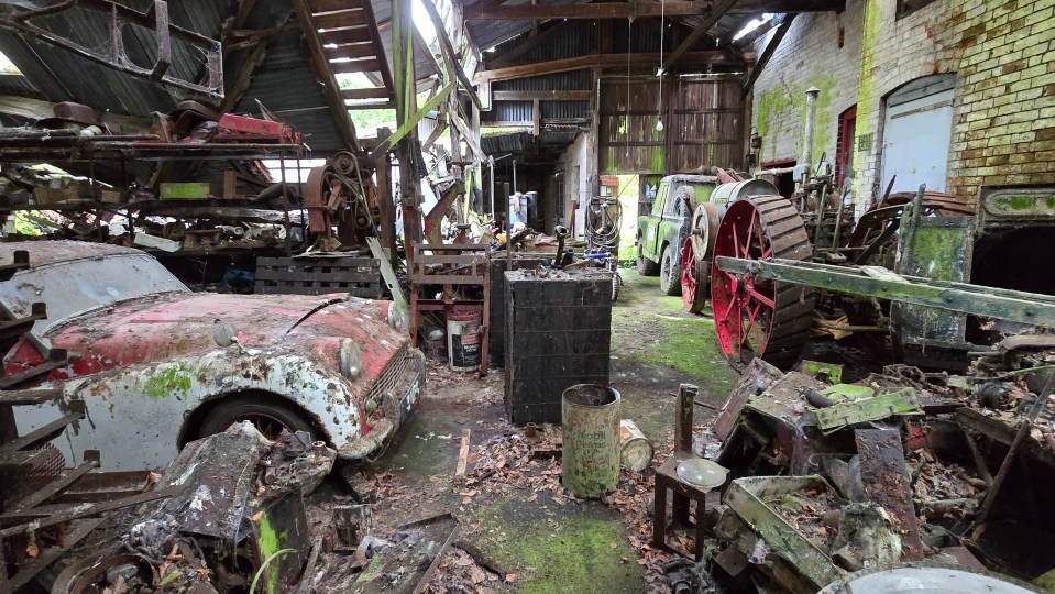 a warehouse filled with lots of junk including a red car