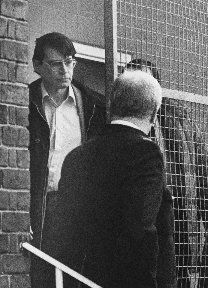 a black and white photo of a man behind a fence