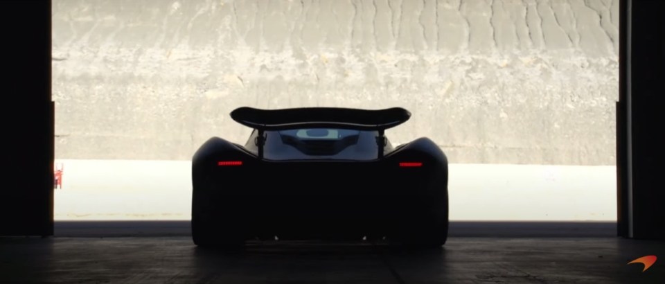 a black car is parked in a garage with a mclaren logo in the corner