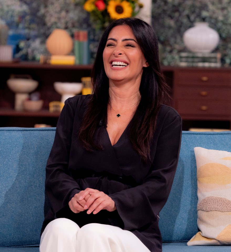 a woman is sitting on a blue couch and smiling