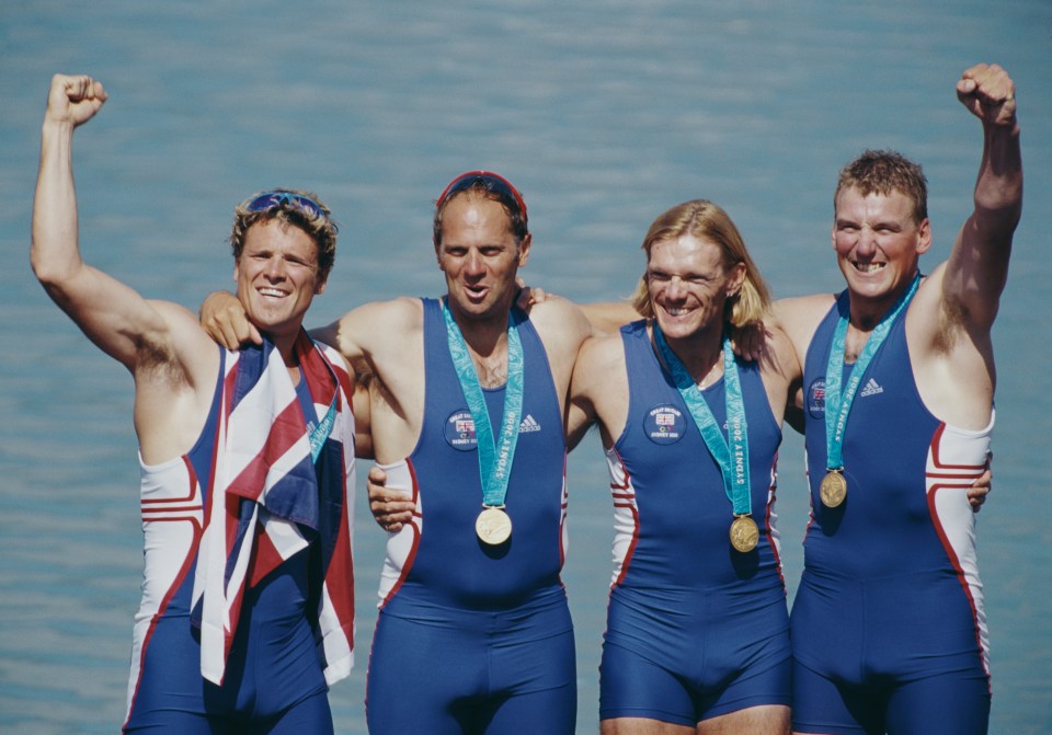 four men are posing for a picture and one has a medal around his neck that says sports 2000