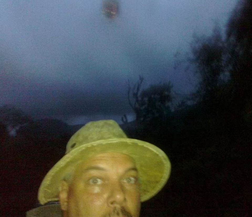 a man wearing a hat looks at something in the sky