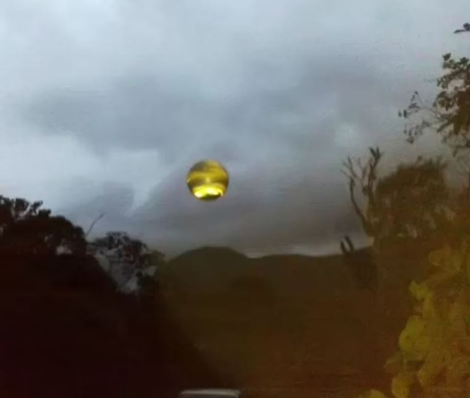 a yellow ball is flying through a cloudy sky .