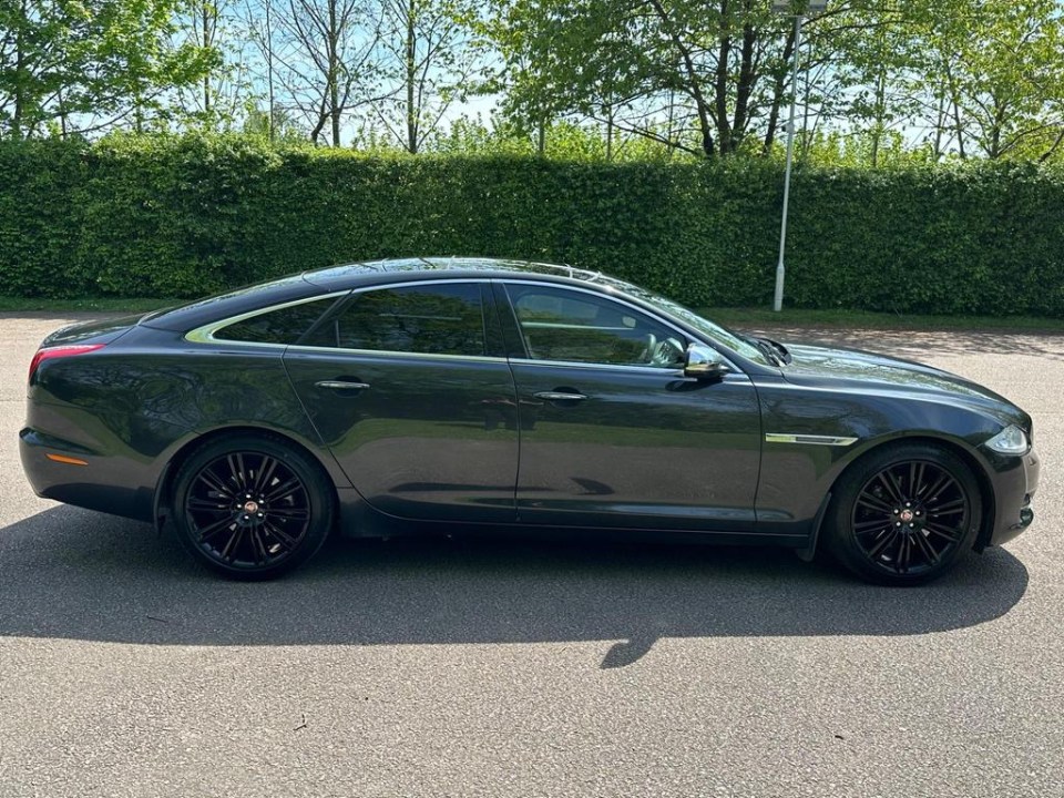 a black car is parked in front of a hedge