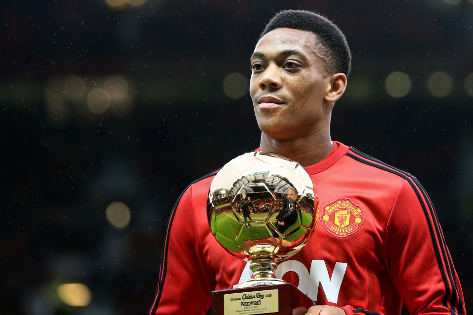 a man in a red manchester united jersey holds a trophy