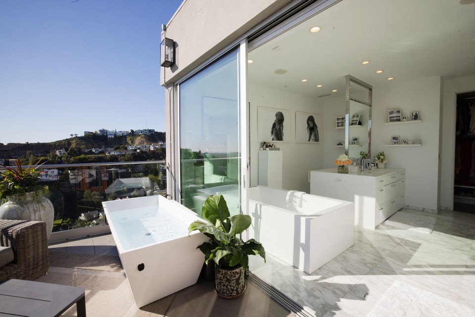 The marble bathroom contains two bathtubs, one inside and another out on the decking