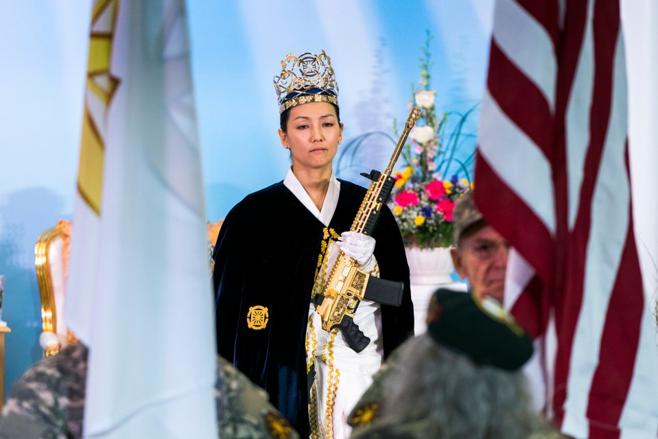 Rev. Yeon Ah Lee Moon of the Sanctuary Church holds a gold AR-15 during a ceremony