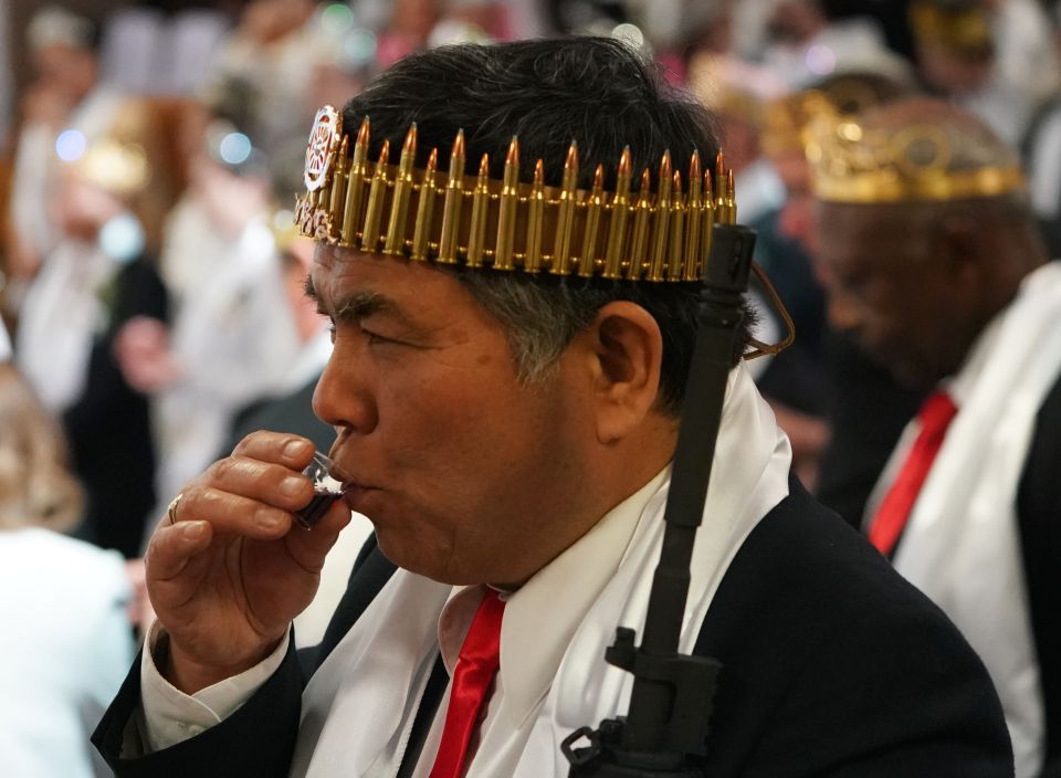 A churchgoer takes communion while wearing a crown of bullets