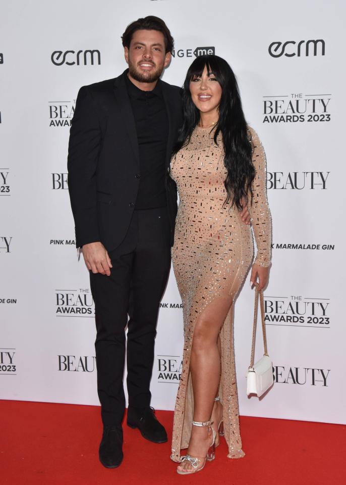 a man and woman pose on a red carpet at the beauty awards