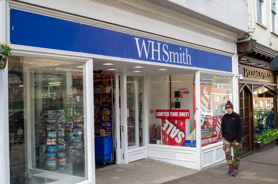 a man walks past a store called whsmith