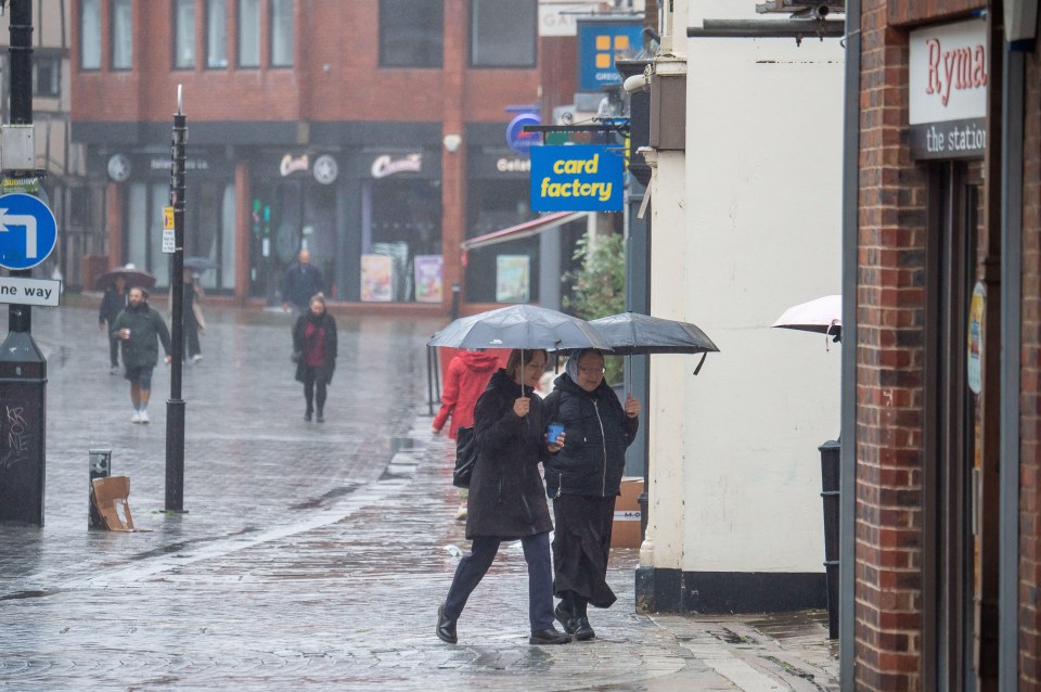 people walking in the rain in front of a card factory