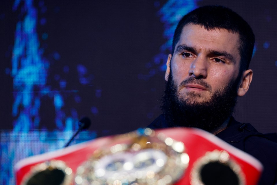 a man with a beard stands in front of a boxing belt with the number 50 on it