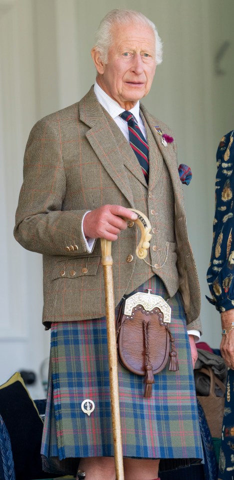 a man in a kilt is holding a cane