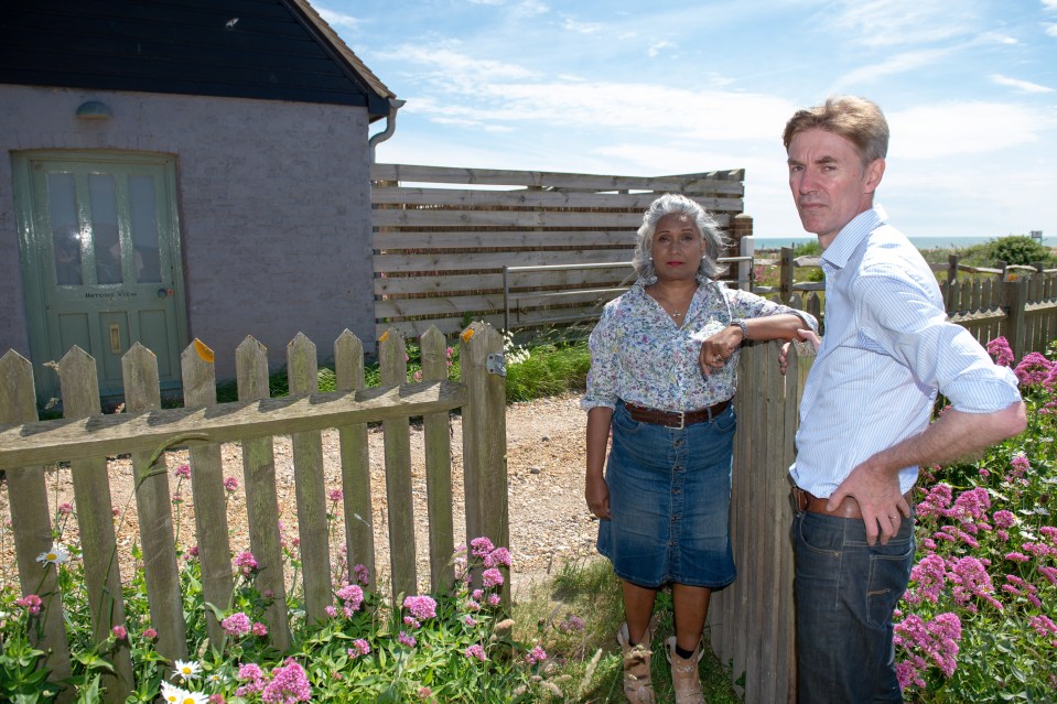 a man and a woman standing next to a wooden fence