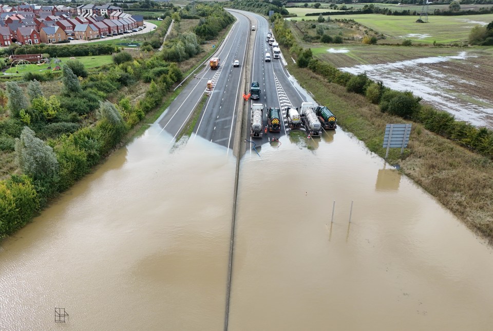 an aerial view of a flooded highway with trucks parked on the side