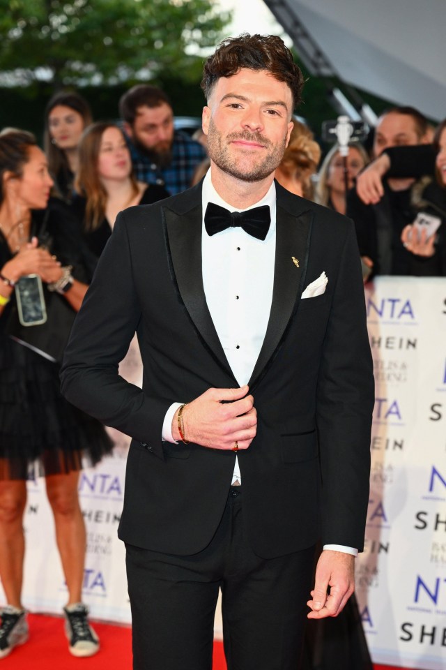 a man in a tuxedo is standing on a red carpet that says nta on it