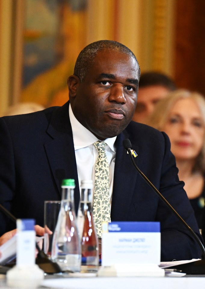 a man in a suit and tie sits in front of a microphone