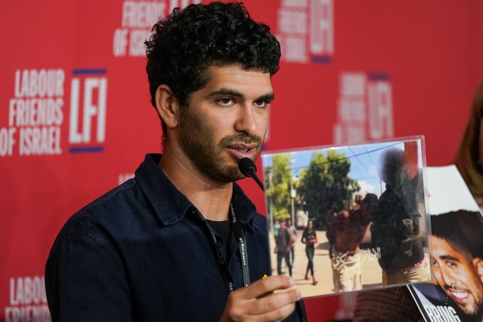 a man holding a picture in front of a sign that says labour friends of israel