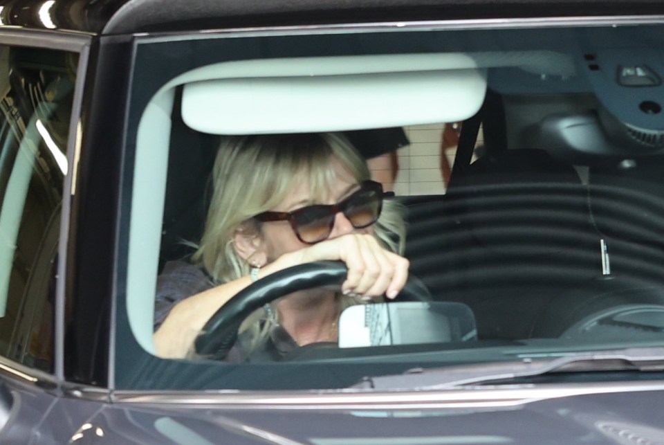 a woman wearing sunglasses sits in the driver 's seat of a car