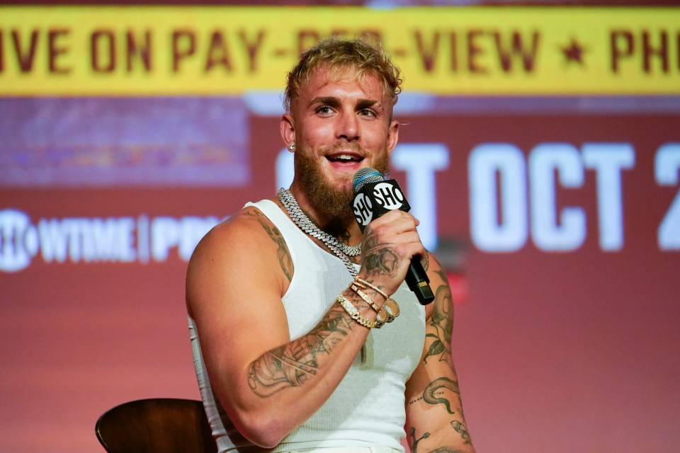 a man speaking into a microphone in front of a sign that says oct 2