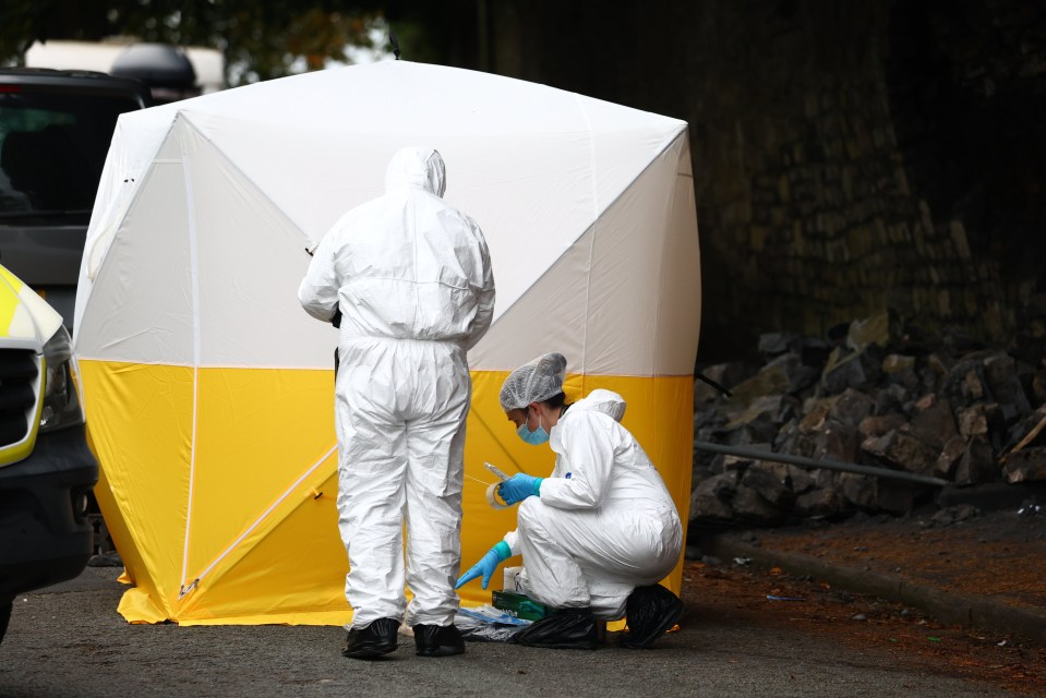 a man in a white suit is kneeling in front of a yellow tent