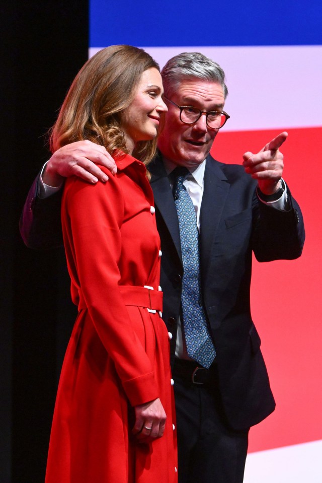 a man in a suit and tie stands next to a woman in a red coat