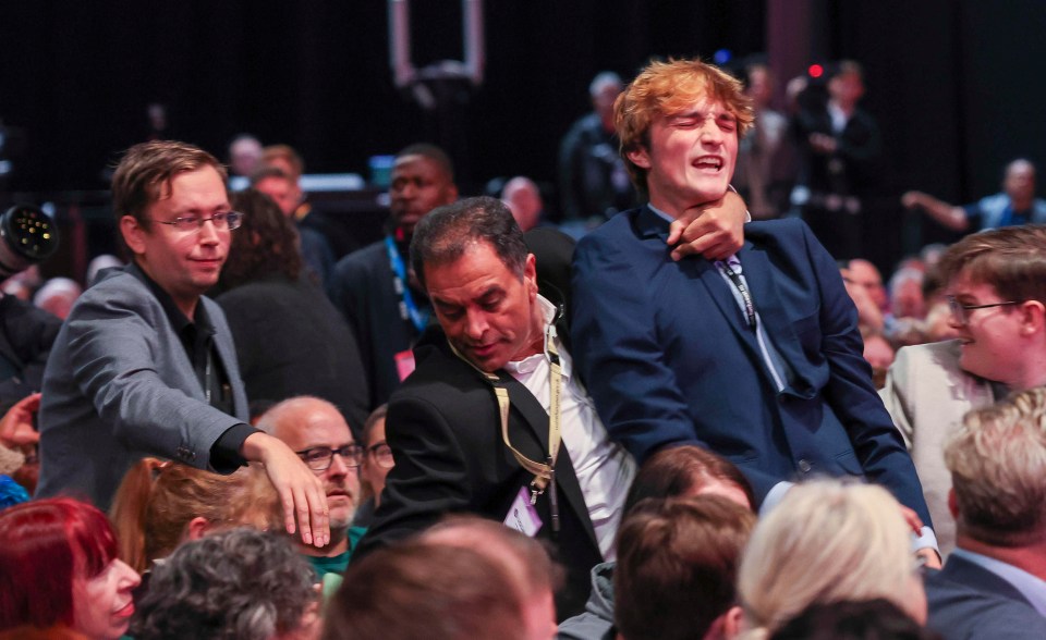 a man in a suit is holding another man in a crowd