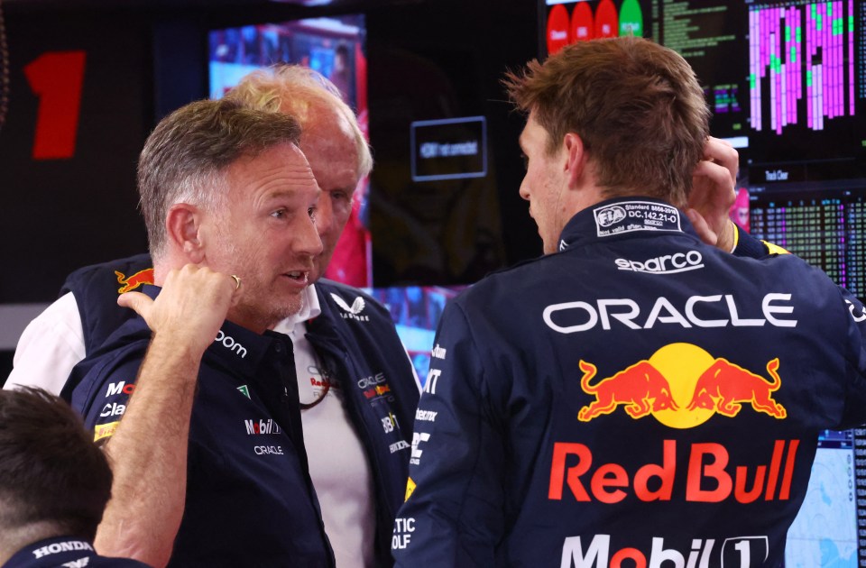 a man wearing a red bull jacket talks to another man