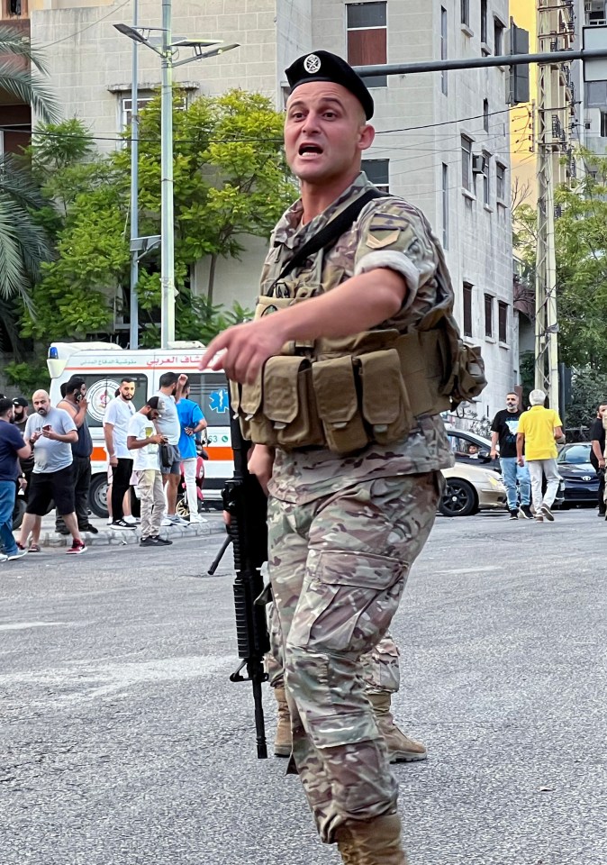 a soldier stands in front of an ambulance with arabic writing on it