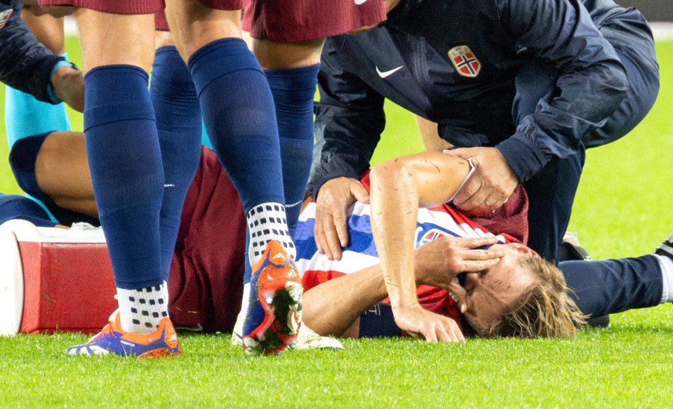 a soccer player laying on the field with a nike jacket on