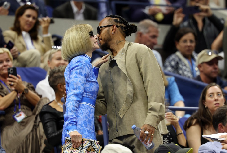 a woman in a blue dress kisses a man in a tan jacket